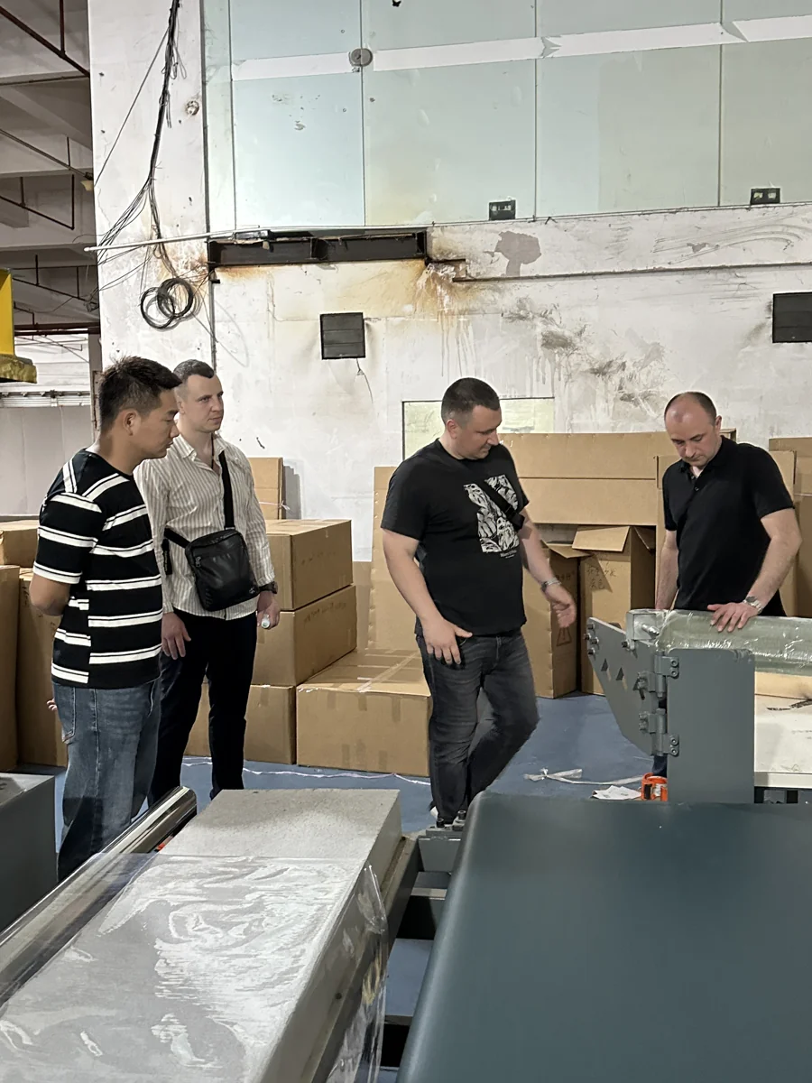 People discussing beside packing equipment in a partner-factory setting