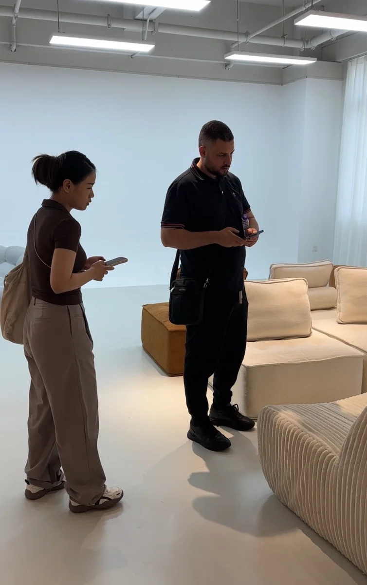 Two people discussing beside upholstered furniture in a showroom setting